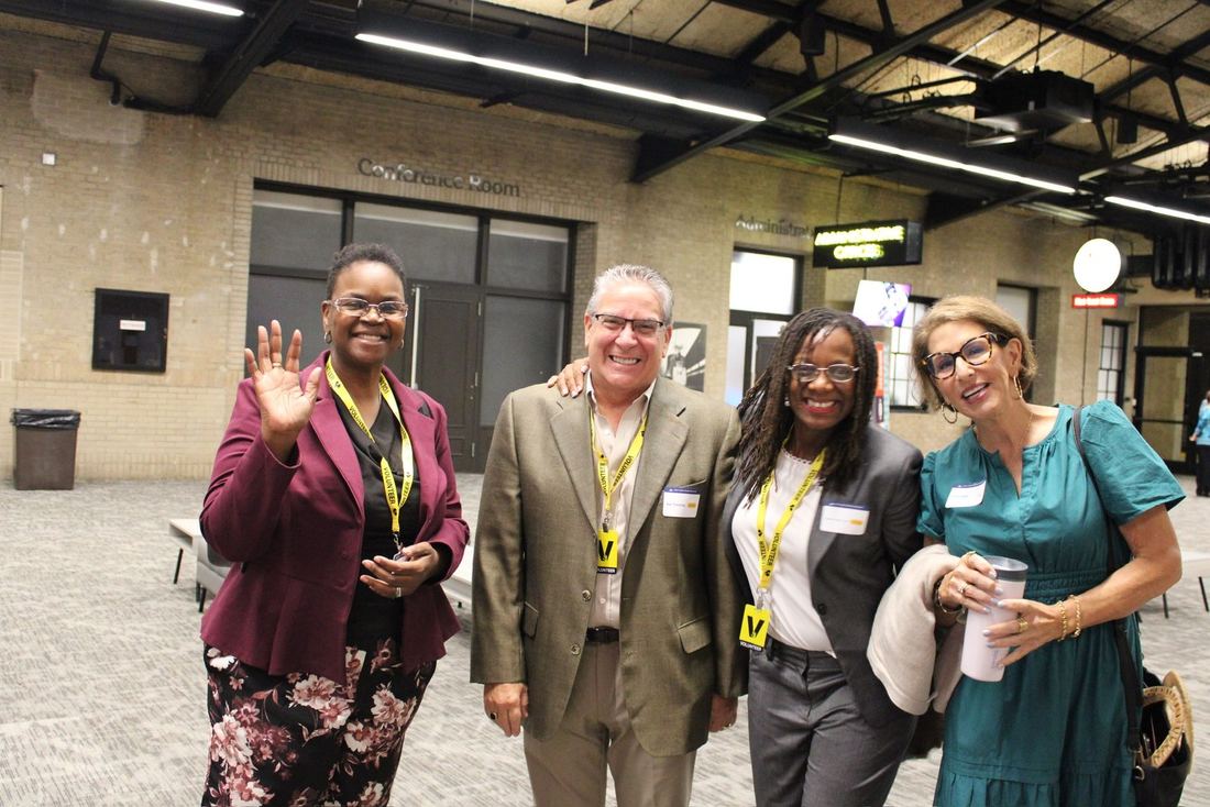 Four guests smiling and waving in the foyer