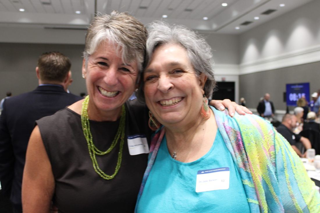 Two women hugging and smiling in the ballroom