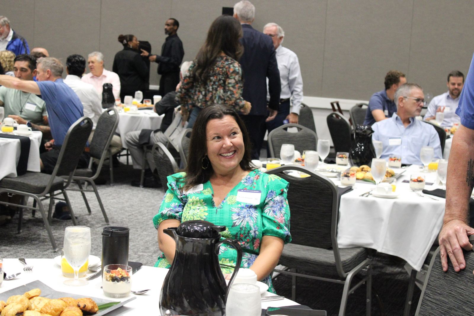 A guest in a green dress beaming at her breakfast table