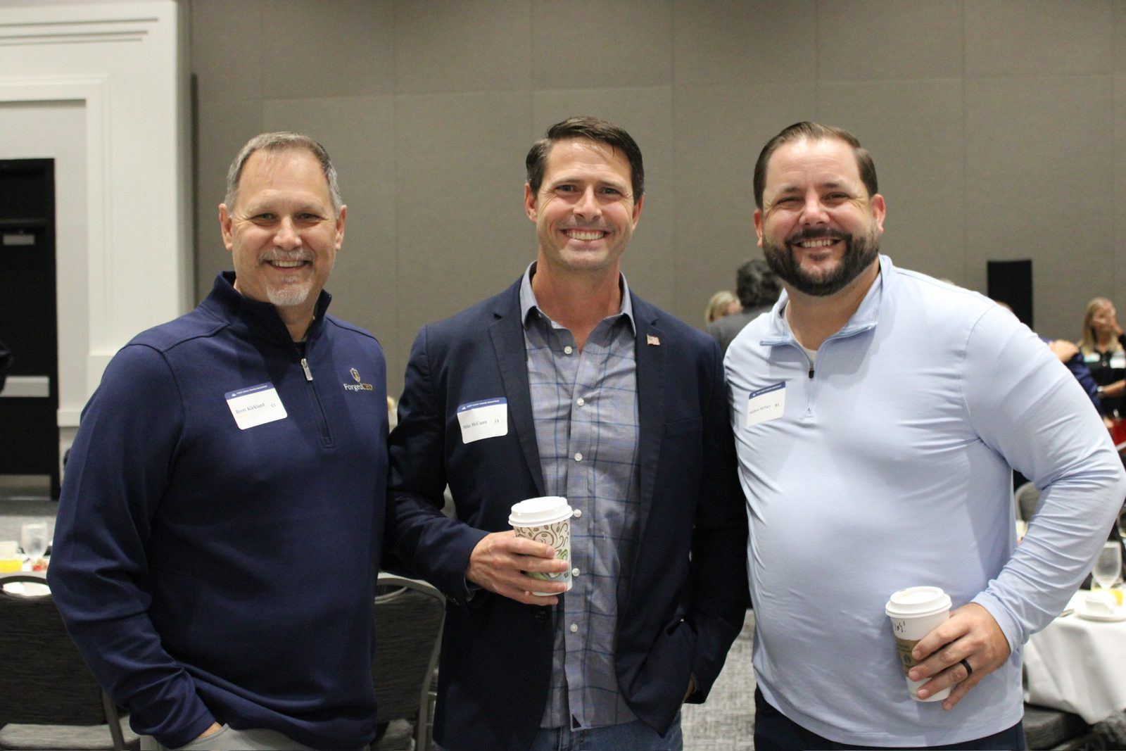 Three table hosts smiling with coffee in hand