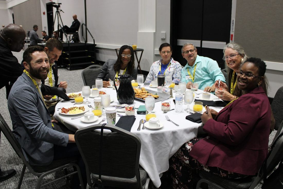 Guests of many backgrounds smiling around a breakfast table