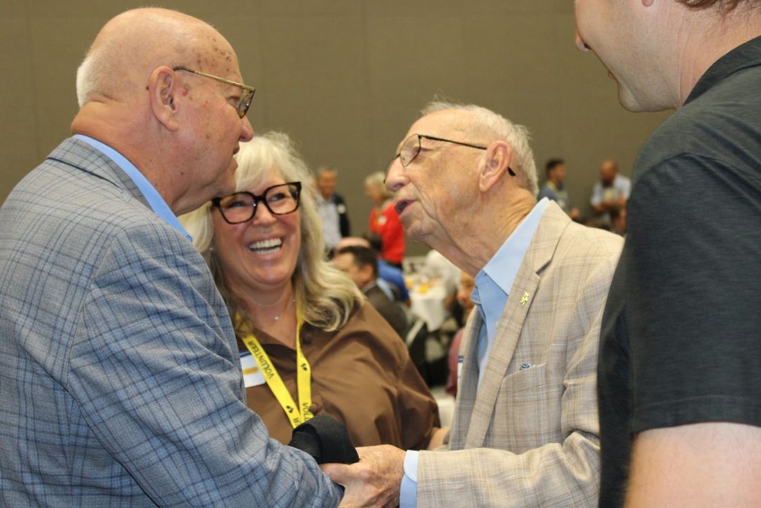 A volunteer laughing with two older gentlemen