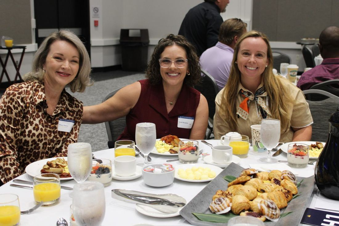 Three women smiling over breakfast